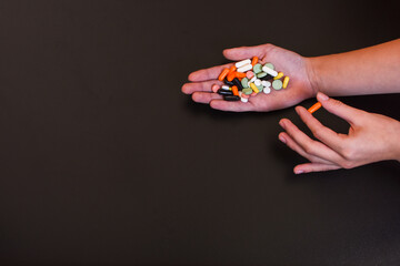 Colorful pills and medicines in the handson black background. Place for an inscription.
