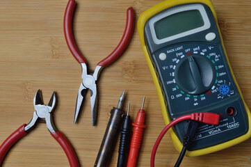 Electric tester and electronics tool kit on wooden background.