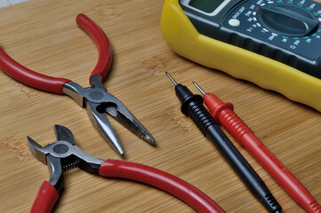 Electric tester and electronics tool kit on wooden background.