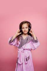 a girl dressed in a terry dressing gown listens to music in big black headphones