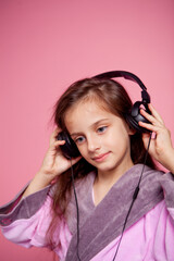 a girl dressed in a terry dressing gown listens to music in big black headphones