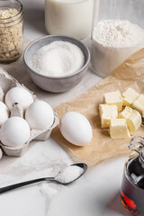Ingredients and tools for home baking on a culinary background. Eggs, flour, milk, sugar, butter, almond flakes, syrup on the kitchen table. Concept of preparation for baking. Homemade pastry. Cooking