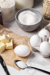 Ingredients and tools for home baking on a culinary background. Eggs, flour, milk, sugar, butter, almond flakes, syrup on the kitchen table. Concept of preparation for baking. Homemade pastry. Cooking