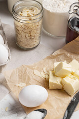 Ingredients and tools for home baking on a culinary background. Eggs, flour, milk, sugar, butter, almond flakes, syrup on the kitchen table. Concept of preparation for baking. Homemade pastry. Cooking