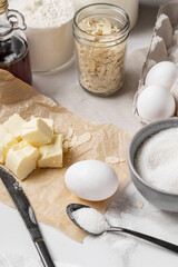 Ingredients and tools for home baking on a culinary background. Eggs, flour, milk, sugar, butter, almond flakes, syrup on the kitchen table. Concept of preparation for baking. Homemade pastry. Cooking
