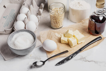 Ingredients and tools for home baking on a culinary background. Eggs, flour, milk, sugar, butter, almond flakes, syrup on the kitchen table. Concept of preparation for baking. Homemade pastry. Cooking