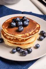 American breakfast. Stack of homemade american pancakes with fresh berry and pouring maple syrup on a white background. Fresh blueberries. Food photo. Breakfast photo. Recipe. Fluffy. Close up view