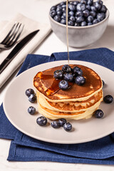 American breakfast. Stack of homemade american pancakes with fresh berry and pouring maple syrup on a white background. Fresh blueberries. Food photo. Breakfast photo. Recipe. Fluffy. Close up view
