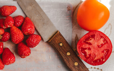 Strawberries, tomatoes  and  knife on a cutting board