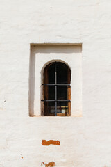 Small dark window in an ancient white stone wall