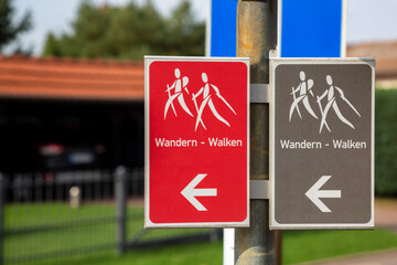 Rotes und graues Schild mit Symbol und der deutschen Aufschrift "Wandern - walken"