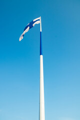 The largest finnish flag in the world and the tallest flagpole in Europe against blue sky, Hamina, Finland. The flag pole is 100 meter high.