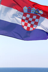 Flag of Croatia, blowing in the wind, above the Adriatic Sea. Selective focus. 