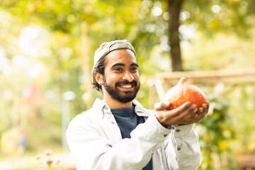 Junger Mann mit Kürbis und Mütze in einem urbanic Garden