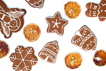Tasty homemade Christmas gingerbread cookie of various shapes with sugar glaze and slices of dried lemon on white background