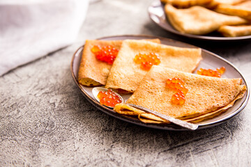 Traditional Russian pancakes with red caviar. Fried crepes with caviar and sour cream