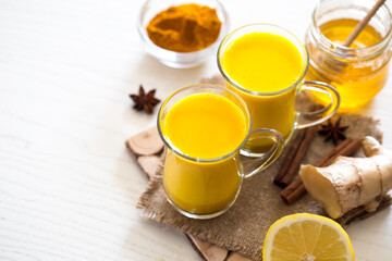 Turmeric tea drinks with milk and honey for beauty and health. Spicy healthy Haldi