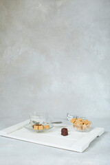 sweet view of brown cane sugar in a sugar bowl and chocolates on a white tray