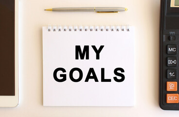 Notepad with text MY GOALS on a white background, near calculator, tablet and pen. Business concept.