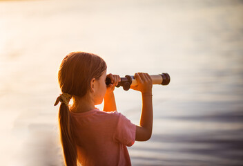 Little girl looking through telescope outside