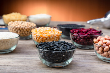 Pile of raw Black Beans in a bowl. black beans on wood background. Dry black beans in dark wooden bowl.