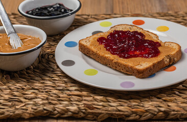 Breakfast. Peanut butter and raspberry jelly sandwich on wooden background.