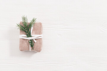 Homemade gift, Christmas present box wrapped in kraft paper decorated natural green fir branch on white wooden table with copy space