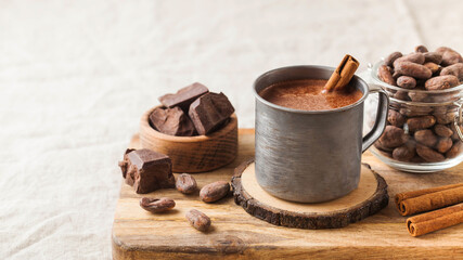 Obraz na płótnie Canvas Hot chocolate in a metal mug with a cinnamon stick on the tablecloth. Copy space