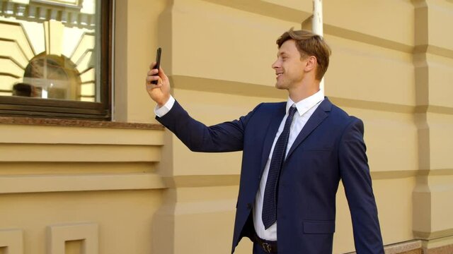 Successful businessman calll video online on mobile phone outdoors