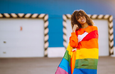 African American lesbian woman holding LGBT rainbow flag.  The concept of happiness, freedom and...