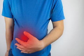 The man is holding onto his swollen belly. Bloating, flatulence, gas, malfunction of the...
