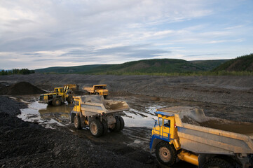Loading of mountain soil into the body of a mining dump truck using a wheel loader, and further transportation of the cargo. Extraction of minerals in the mountainous region of Eastern Siberia