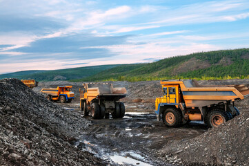 Loading of mountain soil into the body of a mining dump truck using a wheel loader, and further transportation of the cargo. Extraction of minerals in the mountainous region of Eastern Siberia © Letopisec