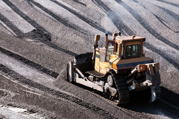 The bulldozer harrows the mountain soil, and then removes the top layer with an industrial bucket. Extraction of minerals in mountainous areas, in Siberia (gold mining)