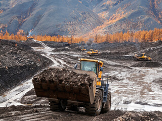 Open pit mining (natural gold) in mountainous areas. A bulldozer collects a pile of mountain soil. Then, wheel loaders transport this mountain soil and dump it into industrial washing equipment in ord © Letopisec