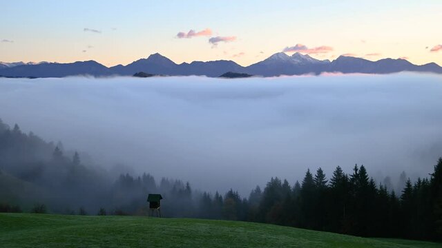 Time lapse low inversion clouds rolling in Alpine valley, Slovenia. Fog covers the landscape. Alps mountains range in the distance. Static shot, wide angle