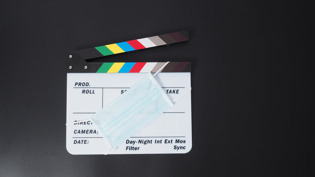 Clapper board or movie slate with face mask. it use in video production and cinema industry on black background.