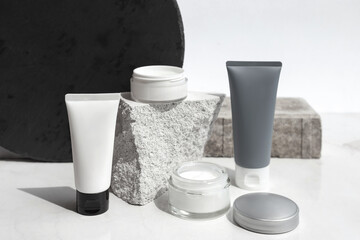 Mock up. Jars, tubes of cream or body lotion, white and gray, on pieces of stone on a white background with leaves. Natural eco organic cosmetics. Treatment spa beauty skincare. Healthcare, medicine