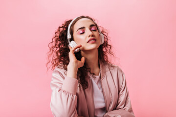 Portrait of girl in pink outfit enjoying music in headphones