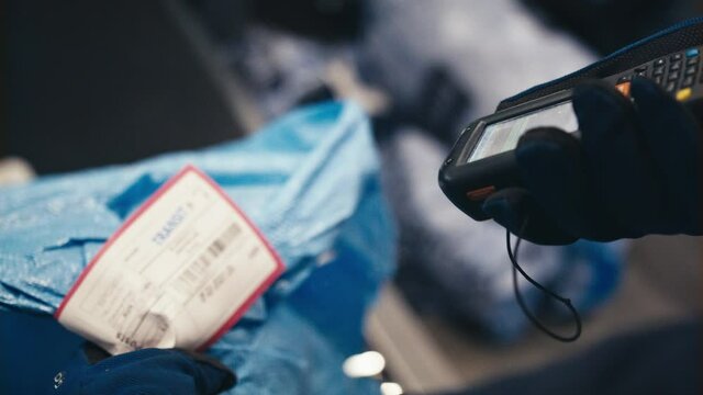 Slow motion of customs worker scanning postal package barcode for electronic processing in warehouse