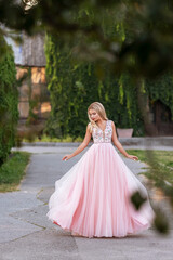 Fototapeta premium Blonde woman with make up in evening dress at park. The skirt of her dress fly on a wind. Sensual fashion portrait with a sunset light