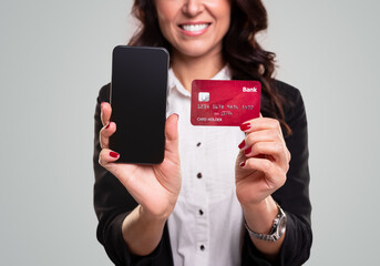 Happy businesswoman showing smartphone and credit card