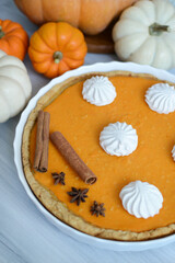 pumpkin pie with cinnamon and cream in a cut. Autumn table setting for Thanksgiving and Halloween. pumpkins, cinnamon sticks, plates, wooden background