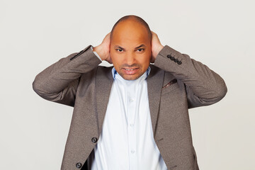Upset man african american businessman in jacket, covering his ears with hands, hearing annoying...