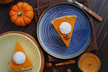 pumpkin pie with cinnamon and cream in a cut. Autumn table setting for Thanksgiving and Halloween. pumpkins, cinnamon sticks, plates, wooden background