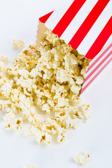 Red and white Popcorn box filled with popcorn on white background
