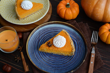 pumpkin pie with cinnamon and cream in a cut. Autumn table setting for Thanksgiving and Halloween. pumpkins, cinnamon sticks, plates, wooden background