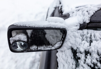 White snow on the mirror of a car