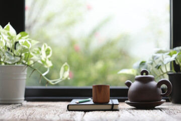 Wooden tea cup with oriental tea pot and notebook with plant pot
