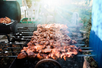 The meat is grilled on charcoal, top view. Barbecue cooking. Smoke rises up from grilled meat